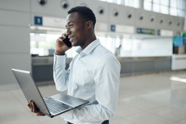 Businessman with phone negotiates while holding a laptop