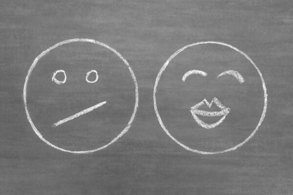 Drawing of a happy face and a sad face represents two-factor theory