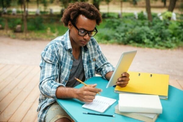 Man learning on outside table from notebooks