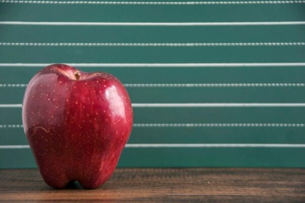 A red apple in front of a chalkboard background