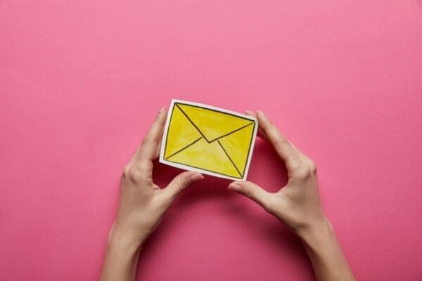 Hands holding cut out email icon with pink background
