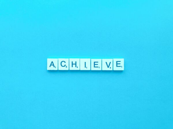achieve spelt out in Scrabble tiles on a blue background