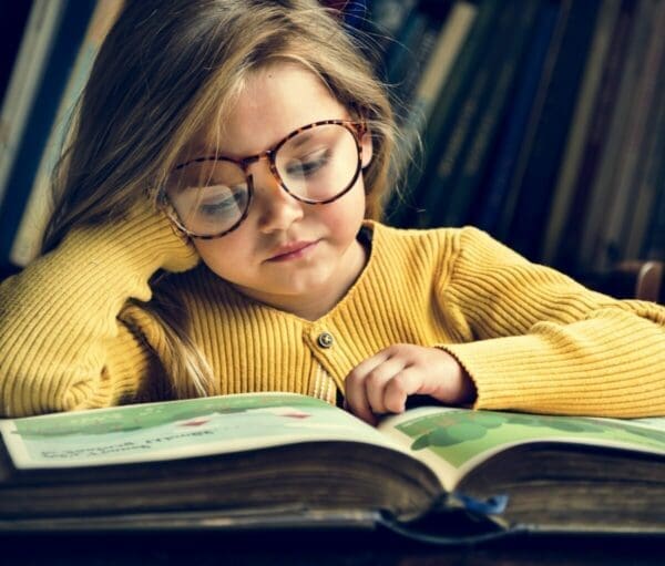 Young girl in glasses reading a story book