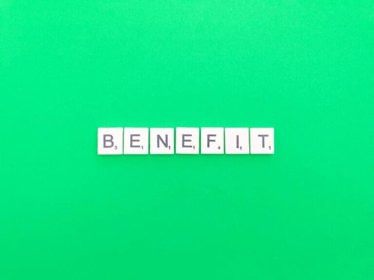 The word benefit spelt out in word scrabble tiles on green background