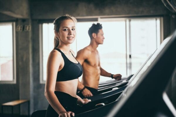 Man and woman running on a treadmill at the gym to improve their health