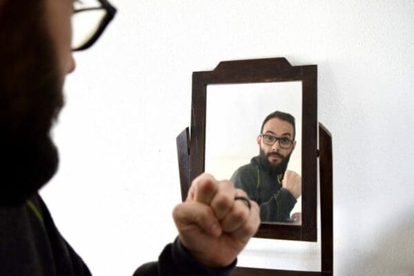 Man looking in the mirror cheering himself on to boost his self-esteem and self worth