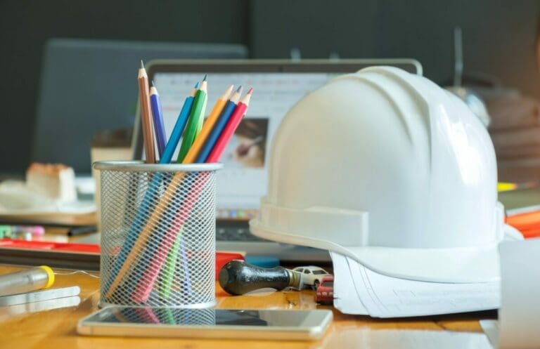 Multi-colored pencils in box with a safety helmet represent safety at work