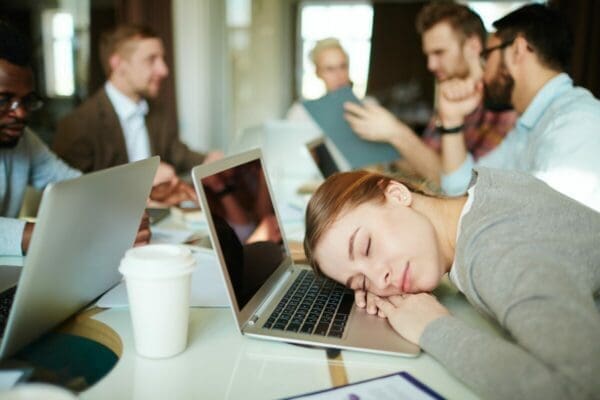 Businesswoman asleep on a laptop at a meeting is not engaged
