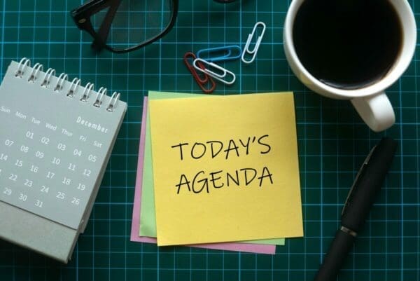 Post it notes with Today's Agenda written on it on a green work table