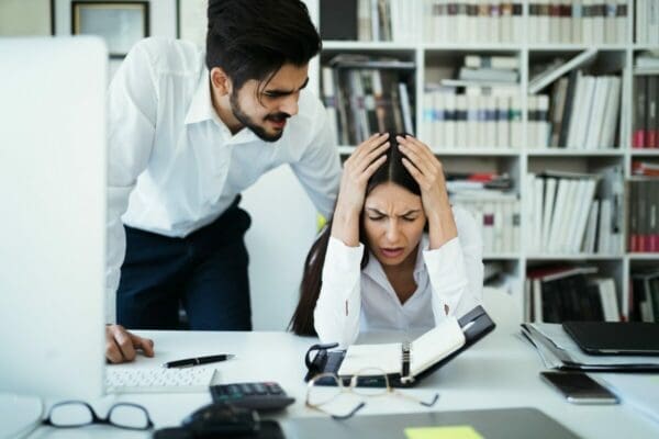 Upset manager micromanaging his stressed female employee