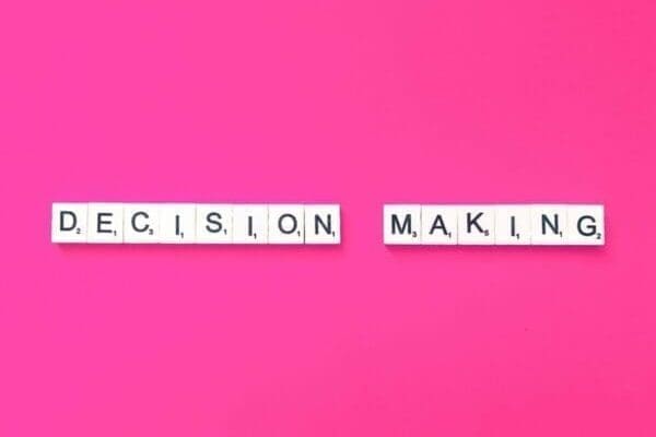 Decision making spelled with white word Scrabble tiles on pink background