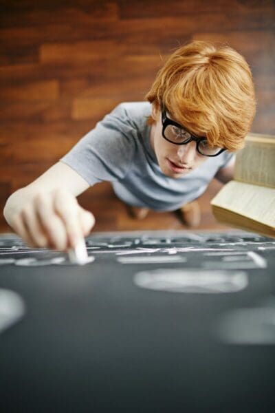 Young boy with glasses writing on whiteboard