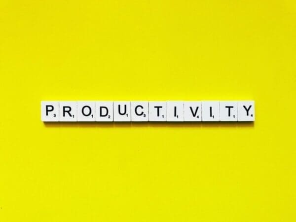 productivity spelled with word scrabble tiles on yellow background