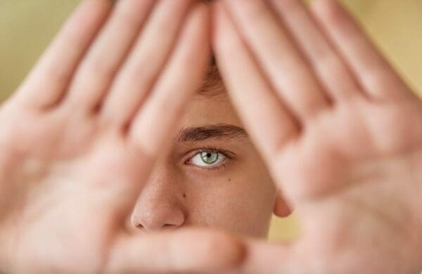 Hands creating a triangle with a person's eyes between