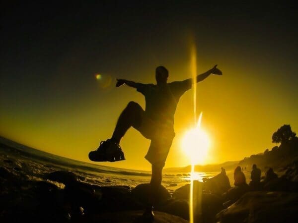 Dark silhouette of a man doing Karate Kid pose in front of a sunset