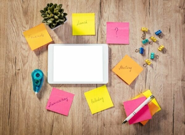 White tablet surrounded by colored post-it notes and office stationery