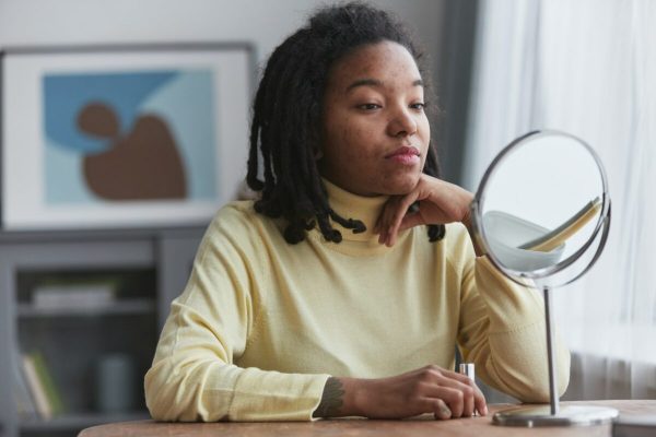 Woman sat at desk reflecting about Gibbs reflective cycle