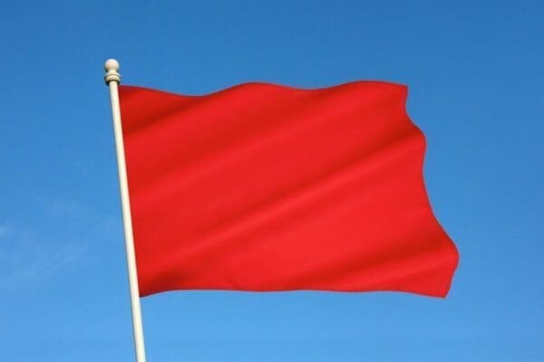 A red flag with gold pole against a blue sky represents red flags