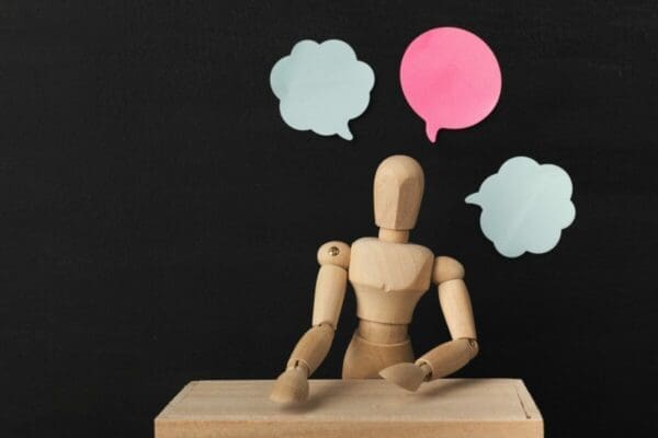 Wooden mannequin with blank speech bubbles represents communication skills