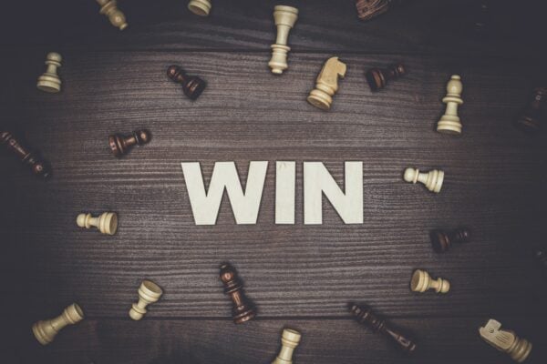 word win on wooden background with chess pieces surrounding