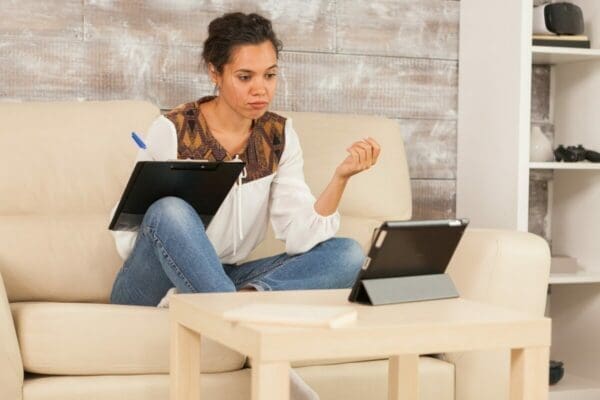 Female work at home employee doing a virtual meeting and taking notes