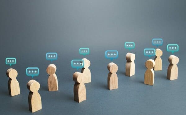 Wooden figures with speech bubbles above their heads represents communication