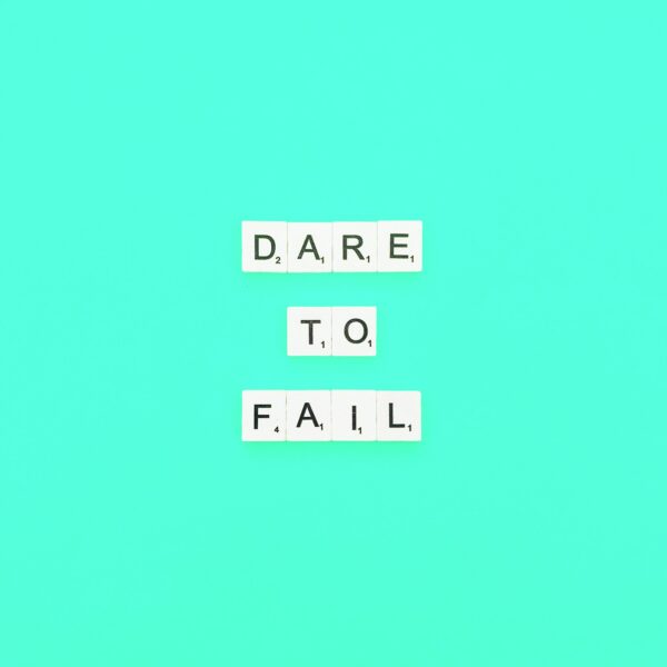 Dare to fail written in Scrabble tiles against blue background