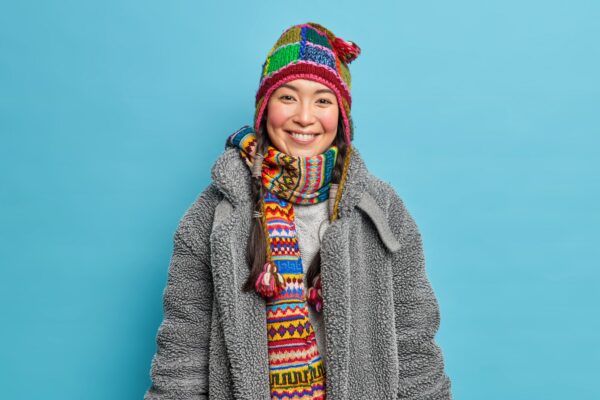 Young woman with a colourful hat and scarf on and a grey coat