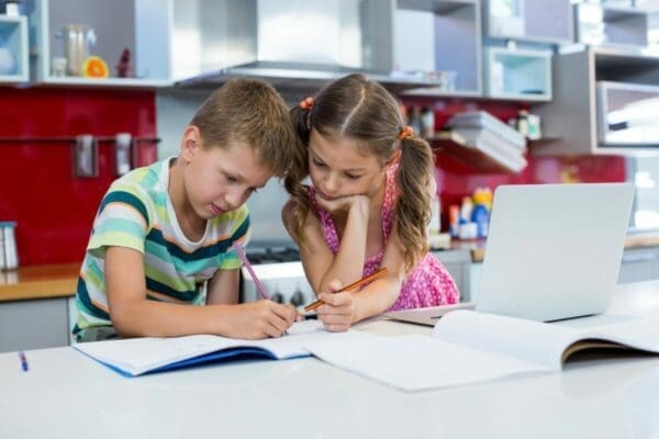 Two children doing homework in a kitchen