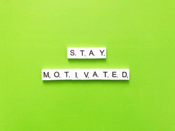 Stay motivated spelled with word scramble cubes on green background