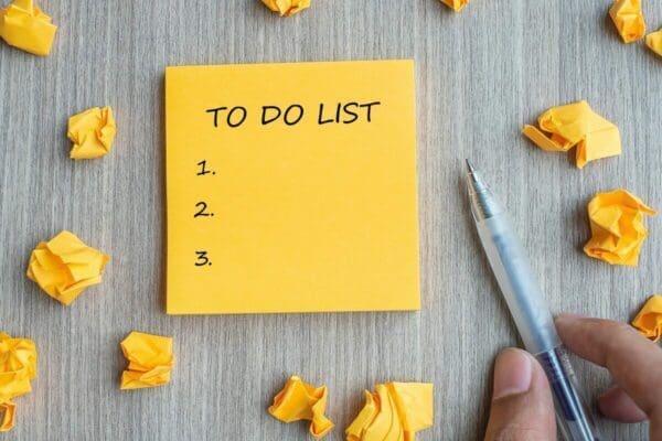 To-do list on a yellow post-it note next to a pen