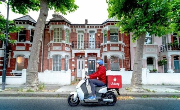 Weezy delivery driver on a bike passing a two story house