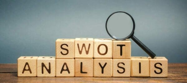 SWOT Analysis spelled with wooden cubes next to a magnifying glass