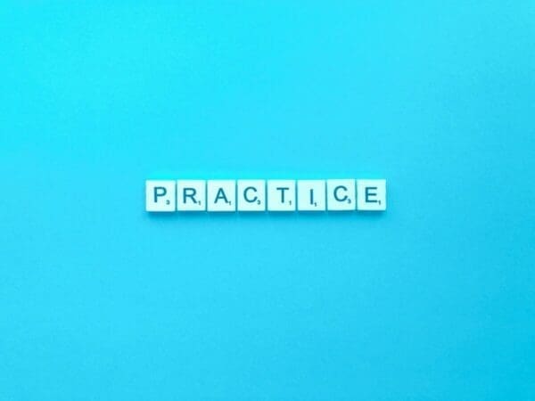 Practice spelled with word scramble cubes on a blue background