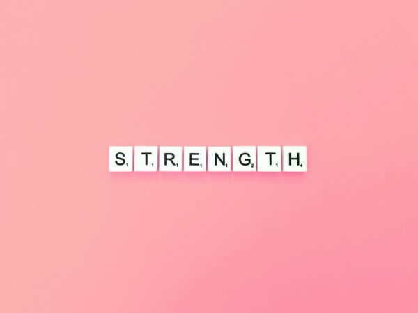 Strength spelt out in Scrabble tiles on a pink background