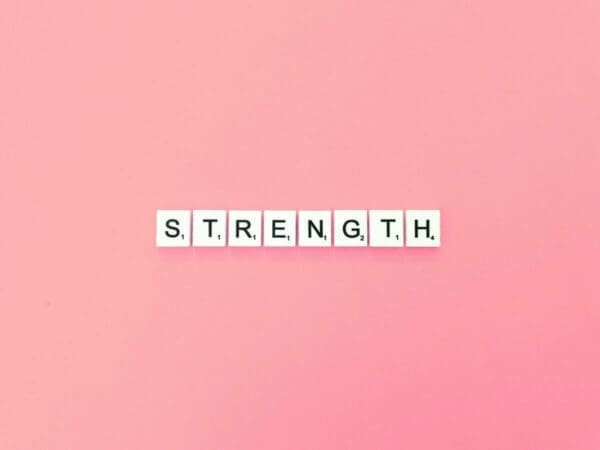 Strength spelled with word scrabble cubes on a pink background