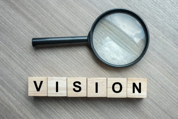 Magnifying glass with word 'Vision' below in wooden tiles