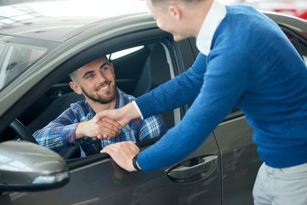 Car seller and customer handshake in car dealership negotiation