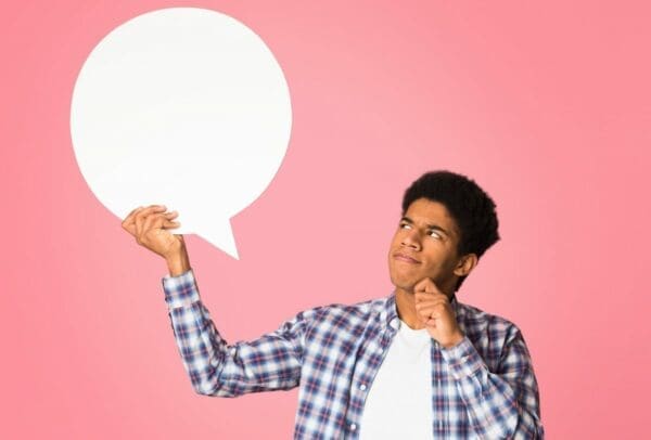 African-american guy looking at blank speech bubble thinking about what is assertive