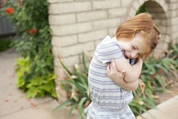 Little girl with her arms around herself does the butterfly hug