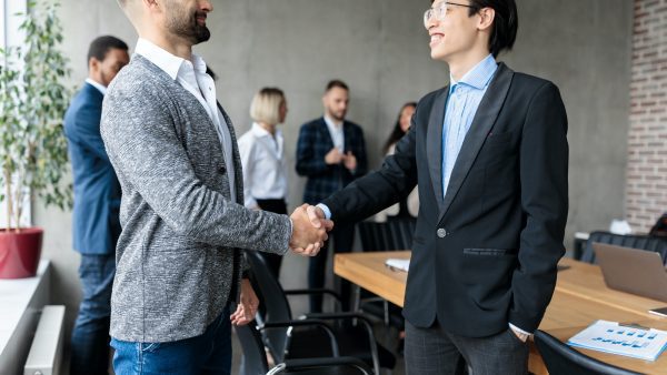 Two Businessmen Shaking Hands After Successful Negotiations In Office