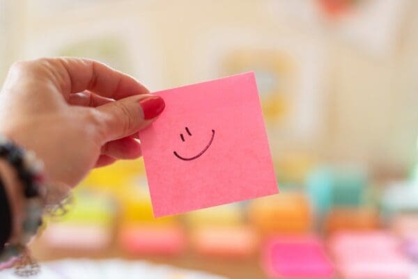 Bright pink sticky note with a smiley face