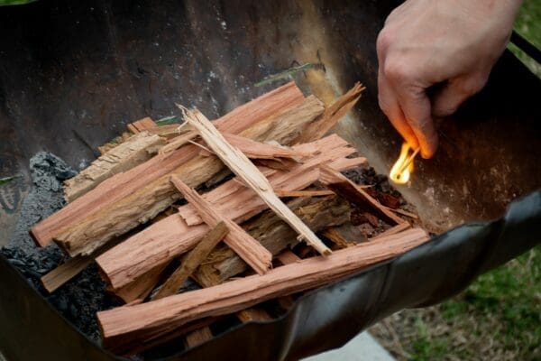 Hand starting a fire with a match stick