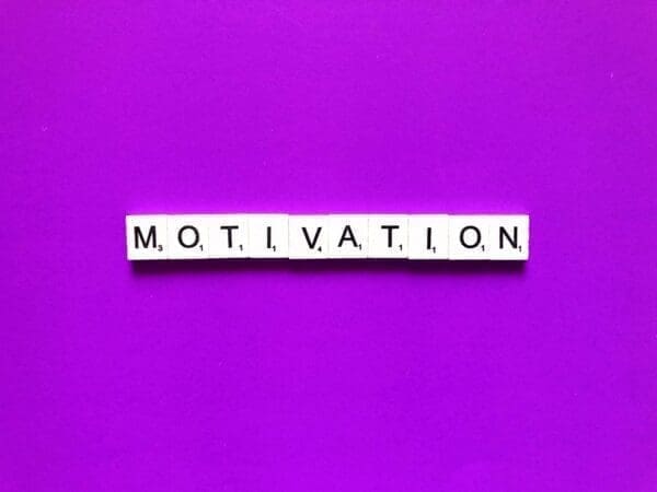 Motivation spelled with word scramble cubes on a purple backround