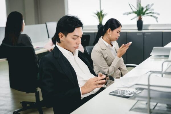 Difficult Employees at work procrastinating by playing on phones