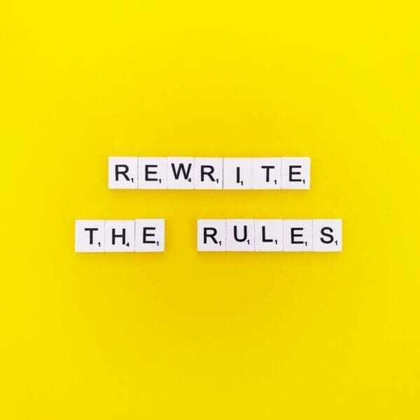 Rewrite the Rules quote spelled with word scramble cubes on yellow background