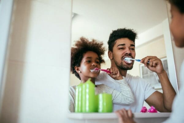 Father brushing teeth with his son to form a healthy habit