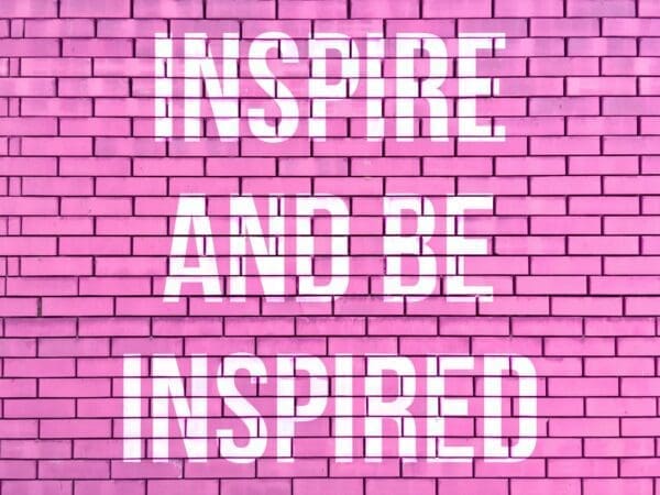 Inspire and be inspired quote on a pink brick wall