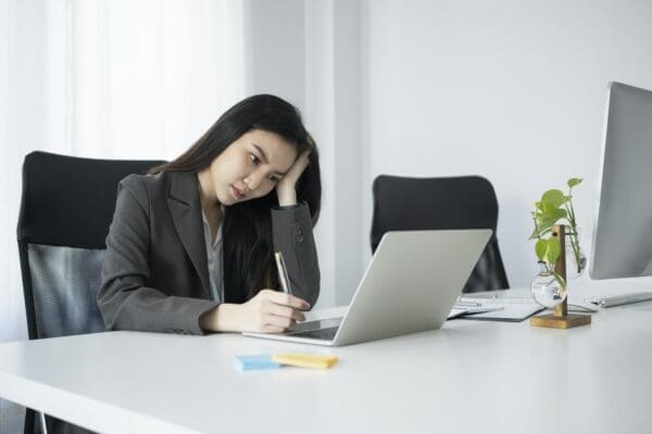 Bored female office worker does E-learning course with laptop in an office is not engaged
