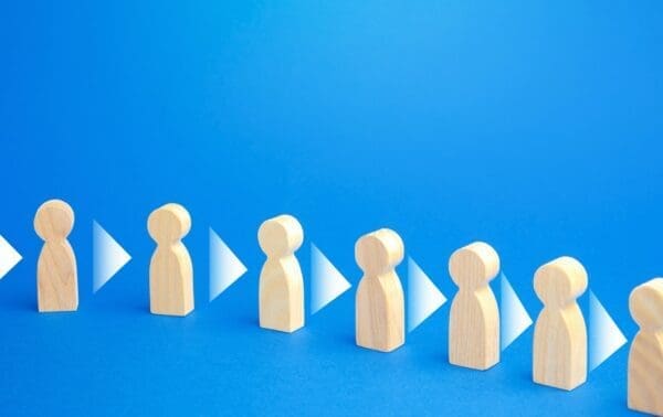 Row of wooden people figures consistently convey information to each other